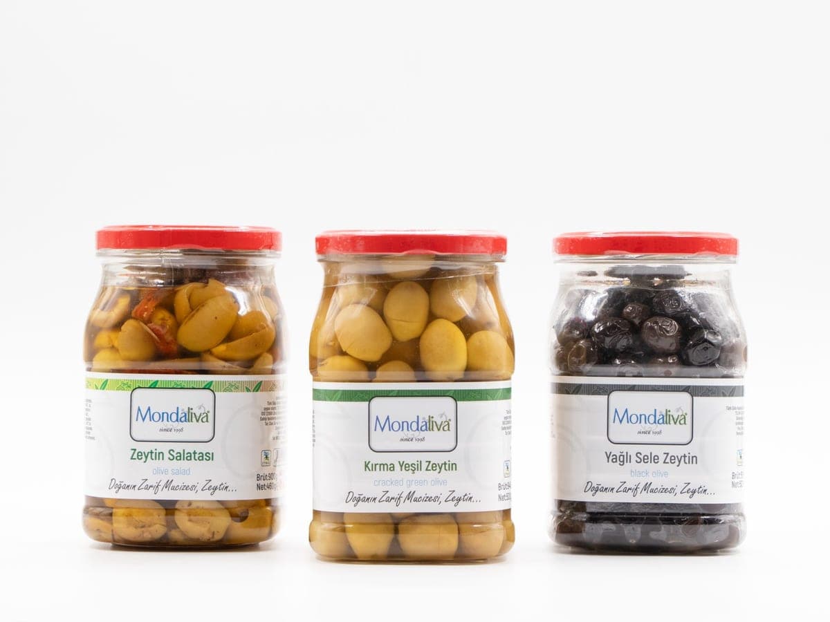 Yan yana üç kavanoz: iki yeşil, bir siyah zeytin